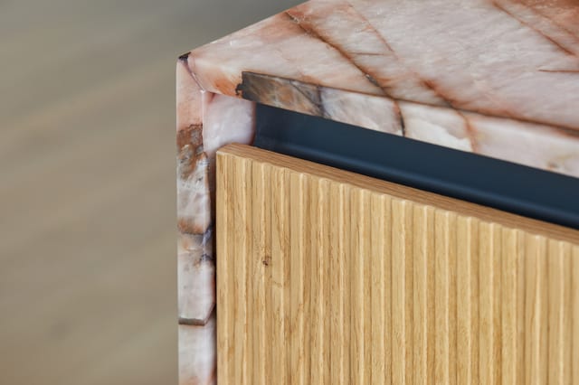 A corner detail where the Cosmopolitan Quartzite worktop meets the routed-oak island with a fine black shadow-gap reveal.