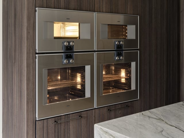 The Gaggenau 400 Series appliance wall at Keston: two wide ovens below with a combi microwave and combi steam oven above, set flush into the Leicht Bahia dark timber.