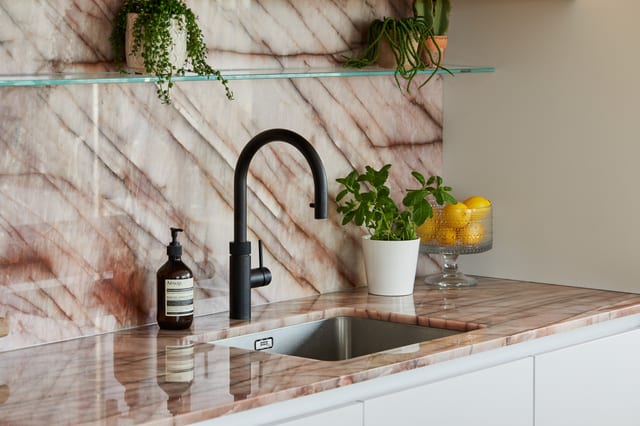 The black Quooker tap over the integrated sink, against the Cosmopolitan Quartzite splashback and worktop.