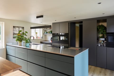 The same Hever cabinetry wall with the concealed passage door slid open, showing the utility and pantry through the doorway.