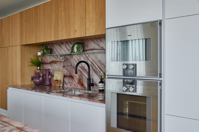 Gaggenau ovens set into the soft white cabinetry beside the Cosmopolitan Quartzite splashback and a black tap.