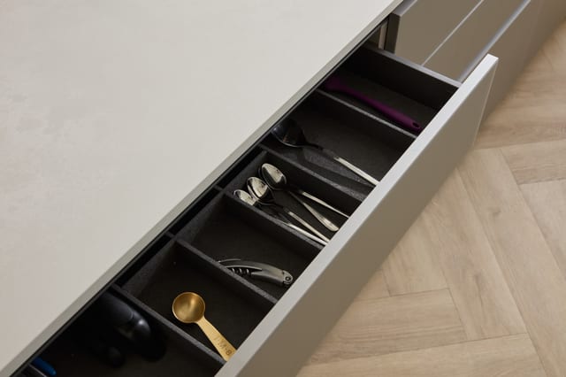 An island drawer in the Oxted kitchen with a fitted cutlery tray, below the Caesarstone worktop edge.