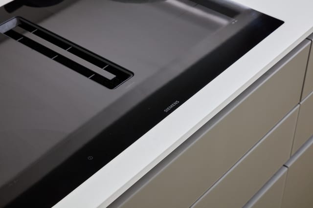 A Siemens induction hob with integrated downdraft extraction, set into the bronze island with a Caesarstone surround.