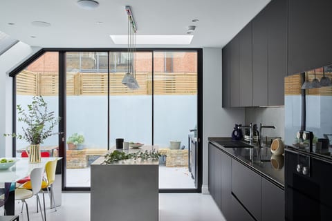 Hammersmith Stainless Steel Island Kitchen — a handmade stainless steel island, a matt black Fenix Leicht run and full-height glazing.