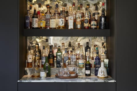 The dedicated drinks area at Eltham — backlit shelves of bottles against a veined marble splashback, with a marble surface below.