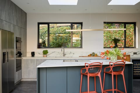Super-matt green cabinetry with concrete-effect surfaces and a ceramic marble-effect quartz worksurface in a Sevenoaks kitchen.