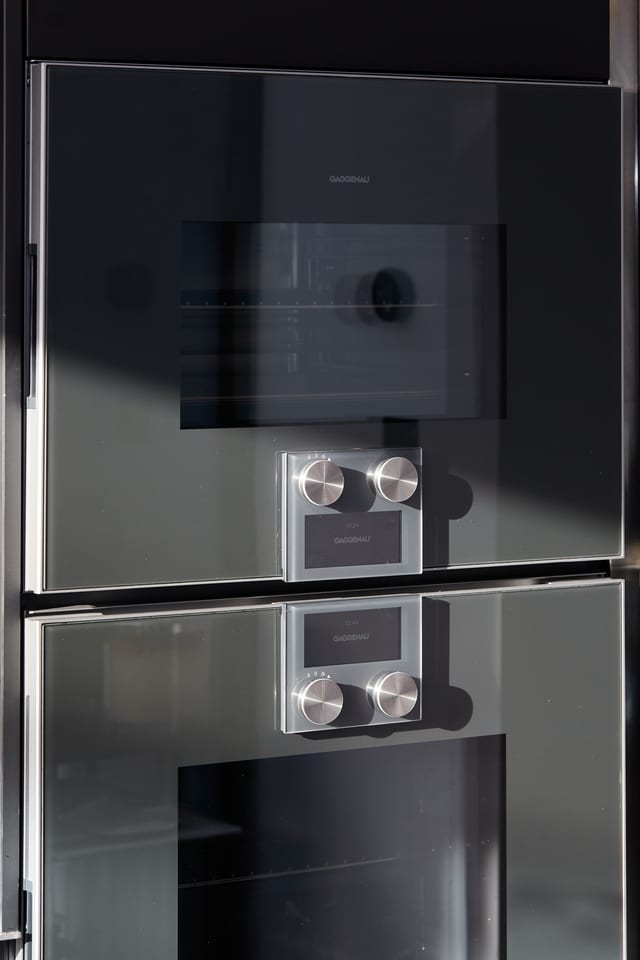 A stacked pair of Gaggenau ovens set into the matt black Fenix cabinetry.