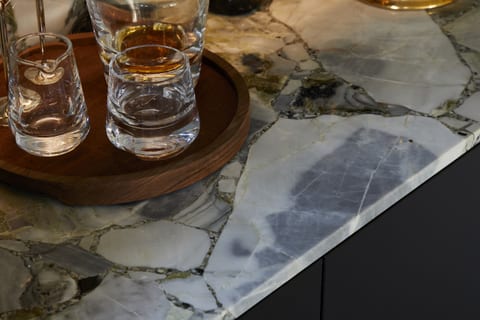 A drinks-area detail at Eltham — cut-glass tumblers on a wooden tray on the veined marble surface.