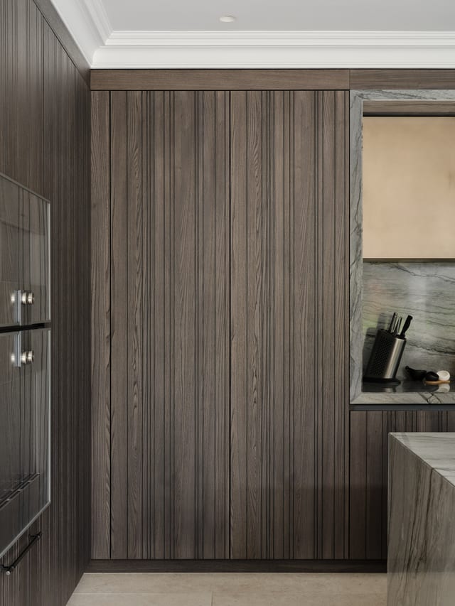 A tall run of Leicht Bahia dark timber cabinetry at Keston with the pocket doors closed, reading as a continuous timber elevation beside the Gaggenau ovens and Platino quartzite.