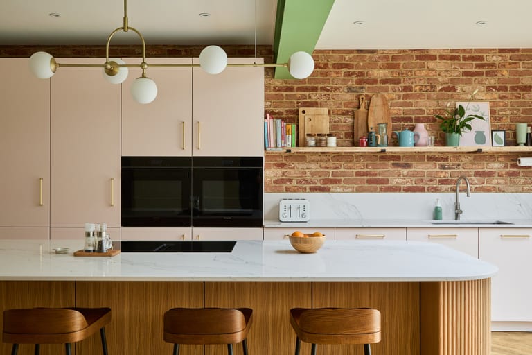 Pink lacquer cabinetry with an oak island and a marble-effect Compac quartz worksurface in a Hayes kitchen.