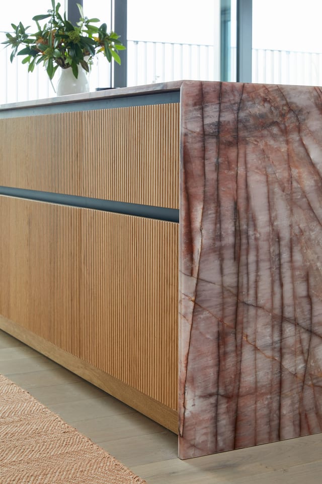The Cosmopolitan Quartzite waterfall end of the island, its pink and grey veining running down over the routed-oak drawers.
